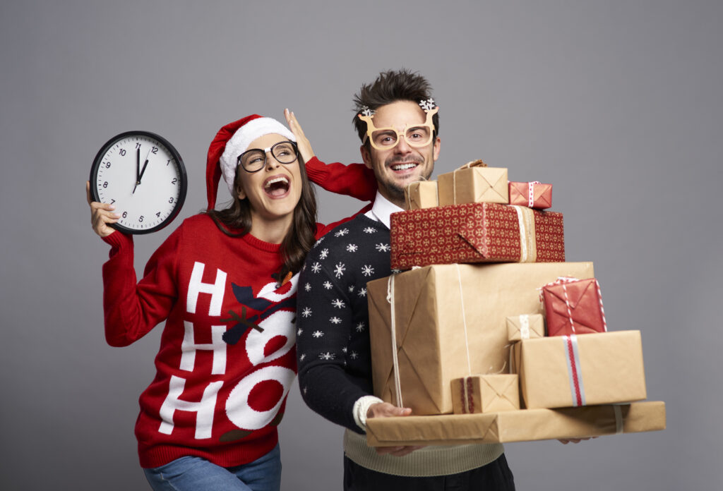 Playful couple holding stack of Christmas gifts